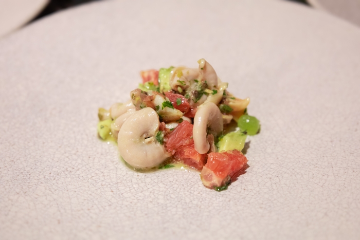 豚モツであるコブクロを、食感が非常に似ている「貝」に見立て魚介やフルーツと合わせた爽やかな前菜として。