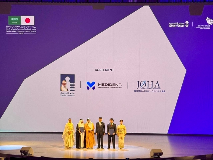 会場スクリーンに表示された提携3者のロゴ(Alfaisal University／MEDiDENT／日本オーラルヘルス協会)。公式プログラムとして壇上で合意。