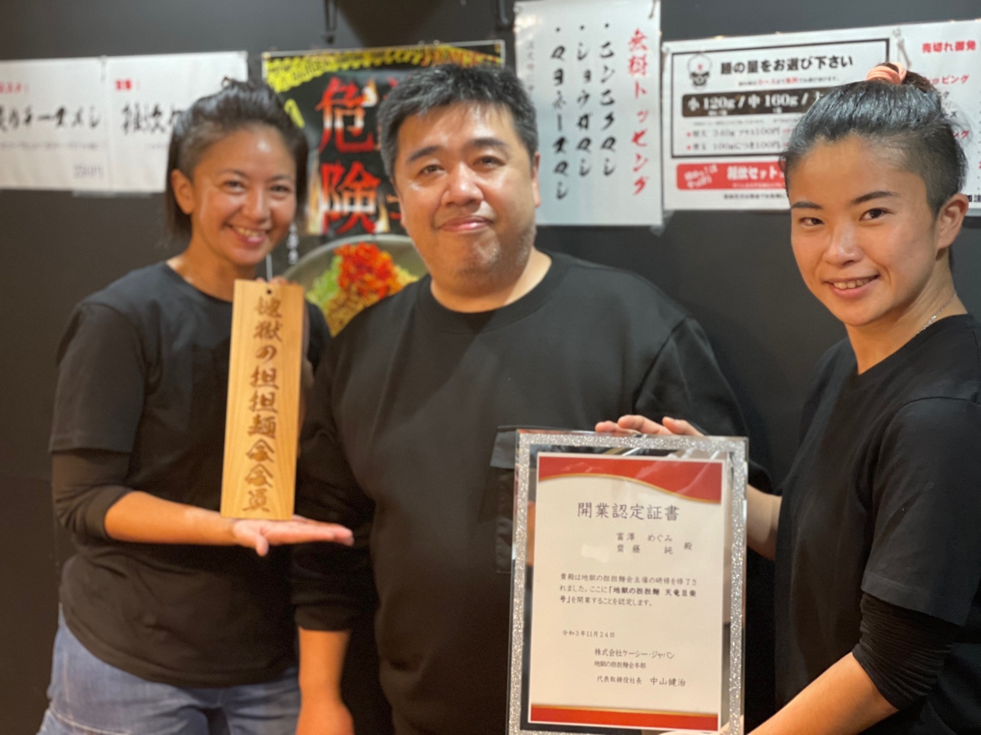 開業許可証授与式 左から富澤オーナー、中山代表、店長豆柴
