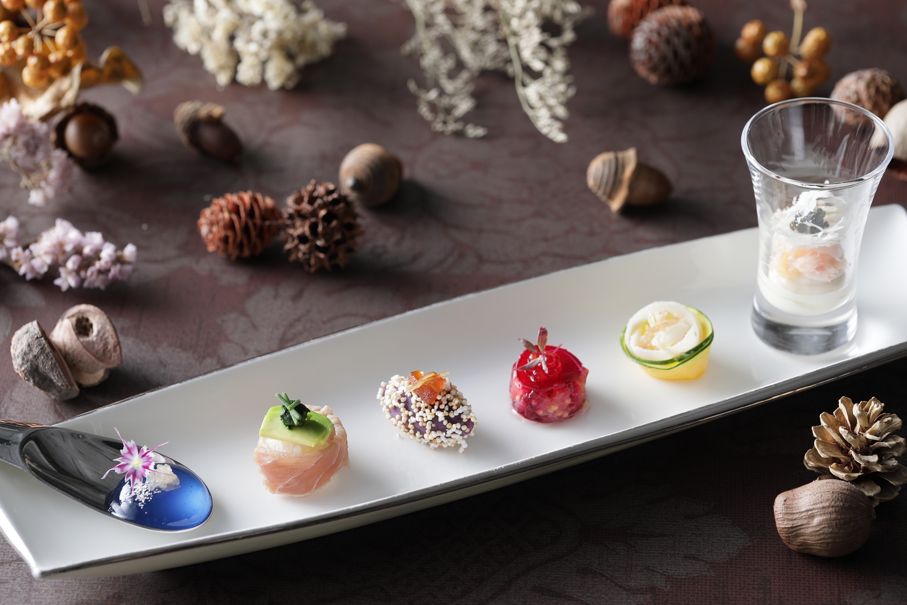Hors-d’oeuvre】  〈ブルー〉甘みのあるマローブルーを酸味の効いたライムキャビアのはじける食感とともに  楽しめる一品。 〈グリーン〉春菊のほろ苦いソースがアクセントの一口大のお寿司。 〈パープル〉じっくり火入れした紫サツマイモにリンゴのカラメリゼとショウガのコンフィで    味わい豊かに仕上げました。 〈ルージュ〉サーモンのタルタルをローストビーツでサンドした見た目も鮮やかなジュエル風に 〈オレンジ〉甘みのあるアオリイカと白ワインでマリネしたサキイカを添えた季節野菜の    鈴かぼちゃと蓮根のサラダ仕立てで食感を楽しめます。 〈ホワイト〉イタリアの魚醤コラトゥーラがアクセントのズワイガニとカリフラワーのムース、ブーケのようにスライスしたカリフラワーを添えて華やかに。