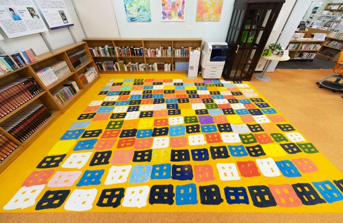 写真:ヘラルボニーの契約作家・渡邊 昌貴氏(多夢多夢中山工房)の作品「ビル」をコモンホールのカーペットに起用