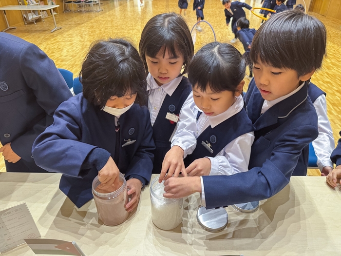 ヨルダンパビリオンの「赤い砂」と「死海の塩」に触れる大阪信愛学院小学校の児童たち