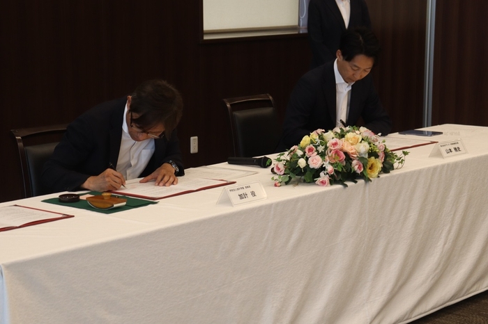 協定書に署名する（左から）加計理事長、山本社長