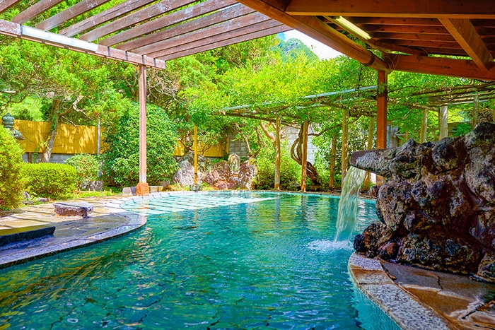 瓢箪型の石造りの大きな浴槽。積み上げた岩から滔々と流れ落ちる豊富な湯量と共にお楽しみください。(鹿教湯 藤館 野天風呂・文殊の湯)