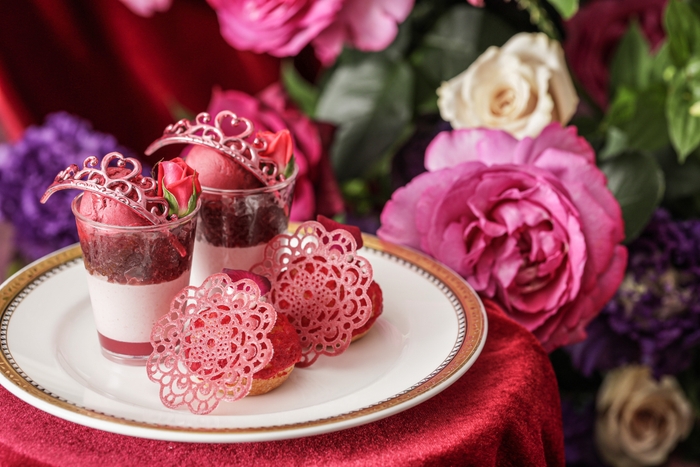 ▲スタンド上段スイーツ イメージ “プリンセスパフェ~薔薇香るルビーショコラ~”は、下からローズジュレ、ルビーショコラとラズベリーのムース、赤ワインジュレ、ラズベリーソルベの層になっているプティパフェ。“ラズベリーローズシュー”は、薔薇香る濃厚なベリーカスタードクリームが楽しめるシュークリーム。