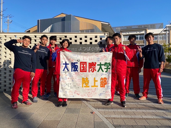 大学駅伝出場にあたり、児童から応援メッセージを寄せ書きした旗をいただく（よつば小学校前にて）