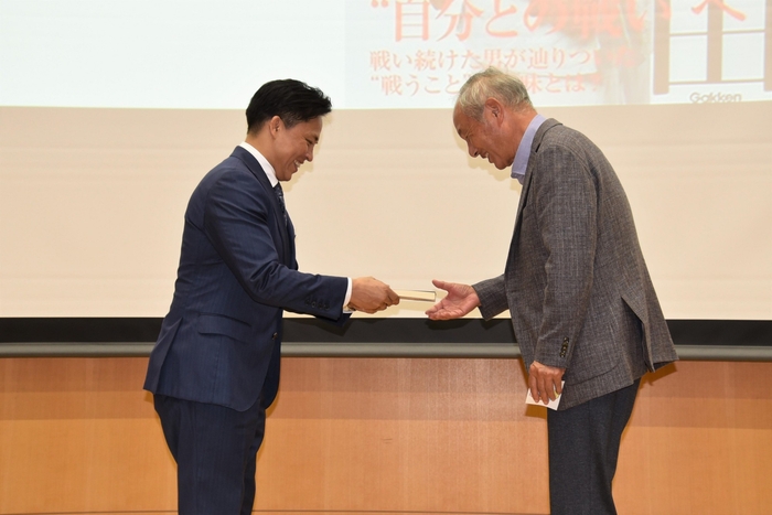 当選者に著書を贈る野村特任教授(左)