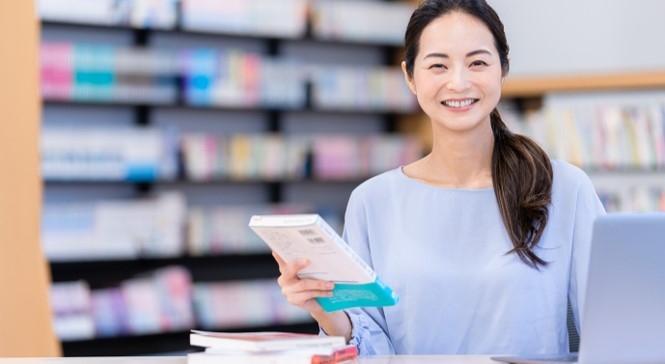 図書館で勤務する司書のイメージ(© shu/PIXTA)