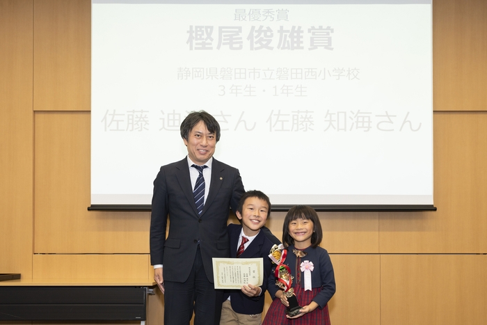 樫尾俊雄記念財団 樫尾隆司理事長と、樫尾俊雄賞を受賞した佐藤 迪洋さん・知海さん 記念写真