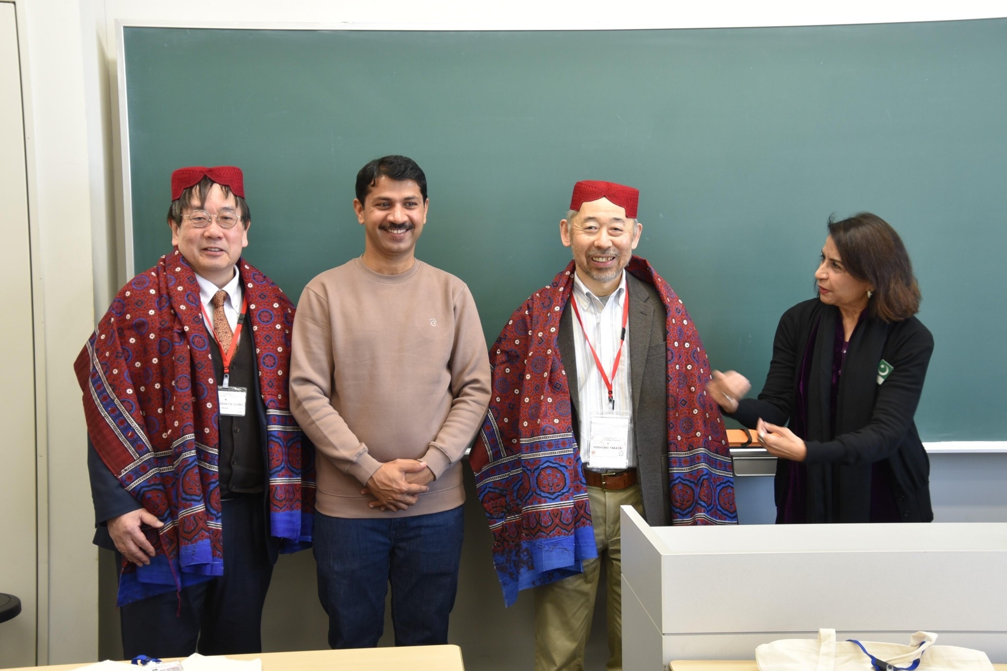 帽子とショールを贈られた神野学部長(左端)と高谷准教授(右から2人目)