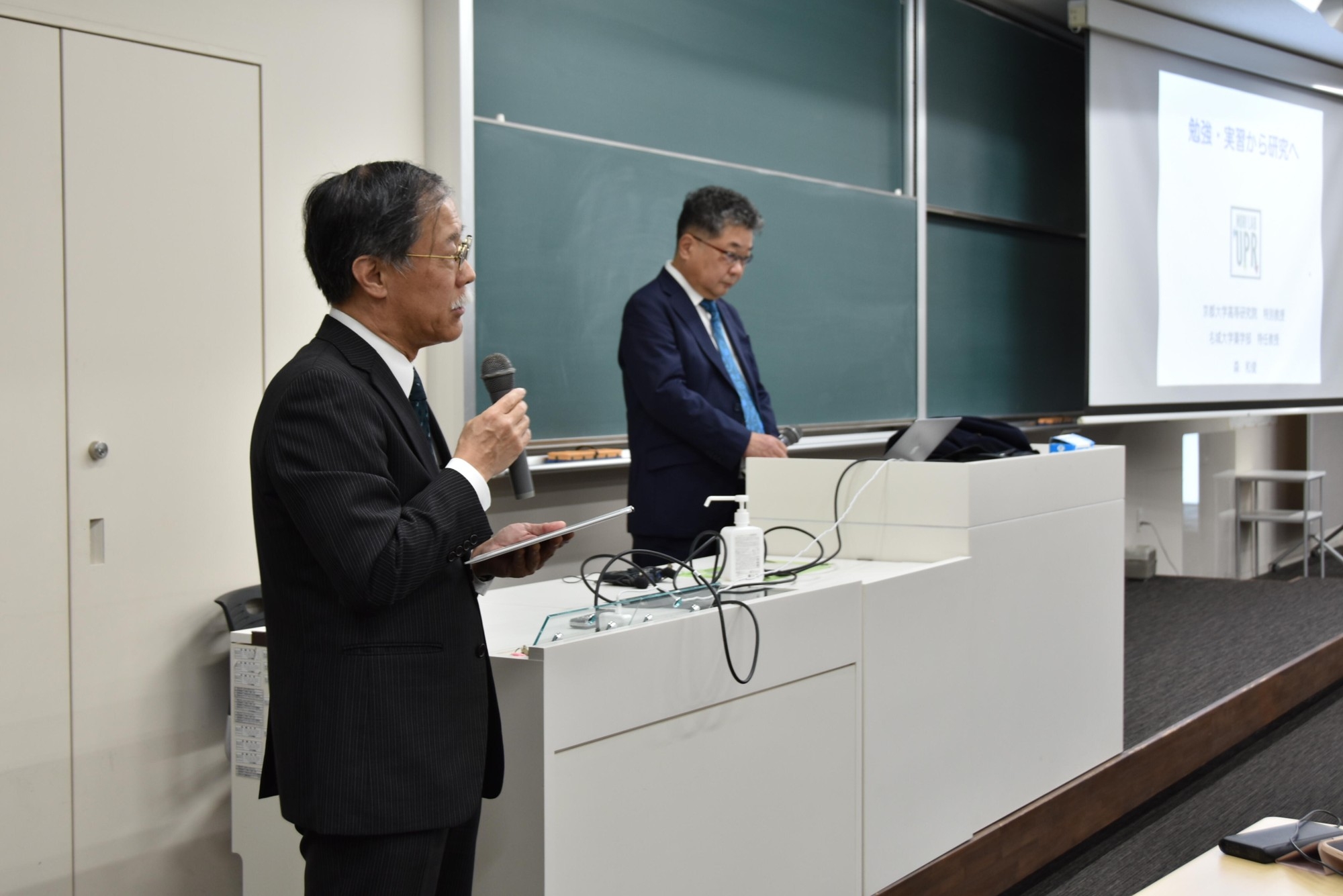 森特任教授を紹介する薬学部の岡本浩一教授(左)