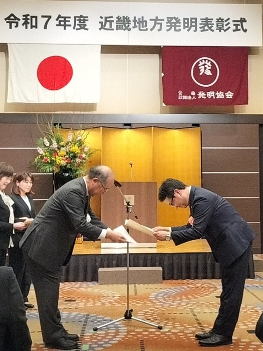 賞状贈呈の様子（左：大阪発明協会会長、右：発明者 足立 将司）