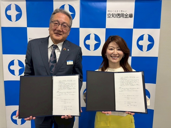 提携書を掲げる国井代表取締役(右)と熊尾理事長