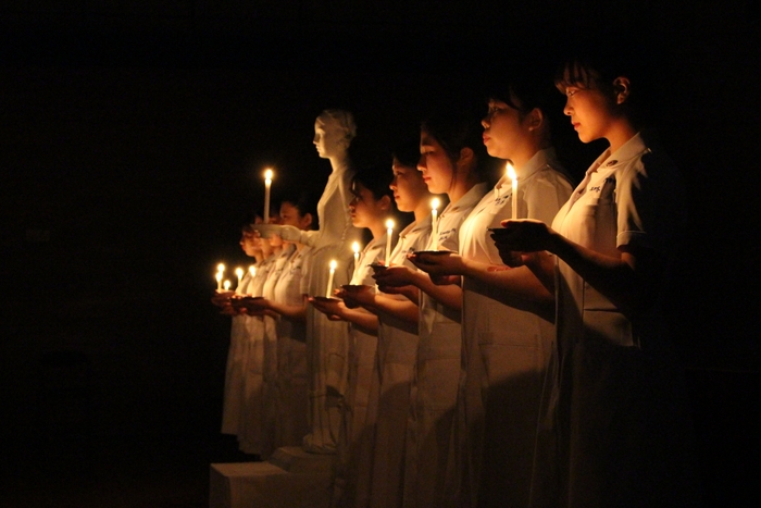 ナイチンゲール像からキャンドルの灯を受け取り宣誓に備える保健看護学科学生