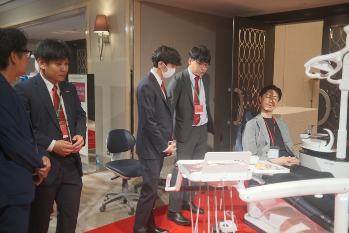 図5：営業社員から最新鋭の歯科用ユニットチェアK5（ケーファイブ)の説明を受ける参加者