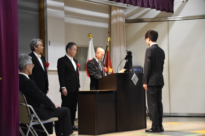 壇上で学長が学位記を読み上げている様子