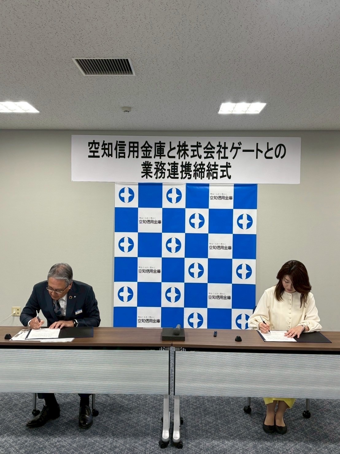 提携書にサインする国井代表取締役(右)と熊尾理事長