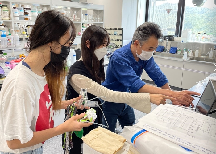 学生たちにデバイス操作の説明をする水野教授(右端)