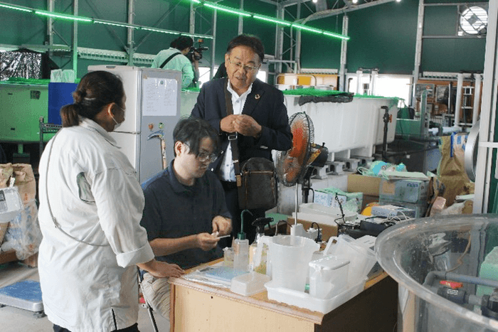 養殖担当の河野さん(左)と三輪さん(中央)にアドバイスする山本准教授