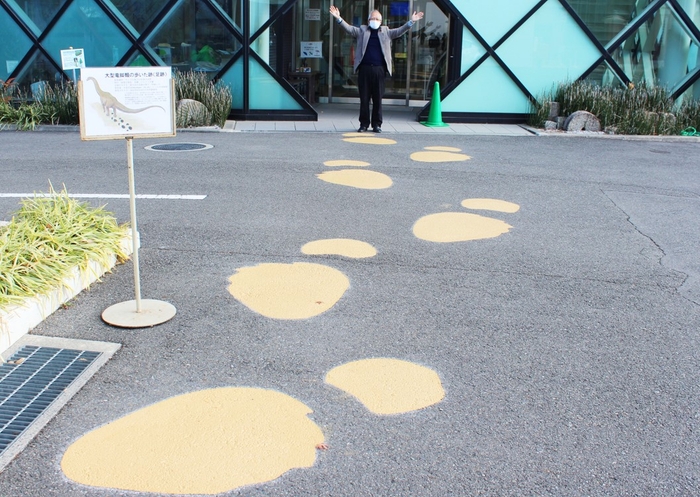 大型恐竜の足跡出現!(後方は石垣館長と50周年記念館)