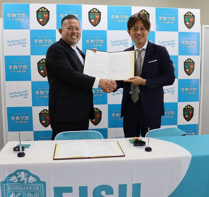 協定書に署名後、がっちり握手する徳岡旭理事長(左)と加計役理事長(右)