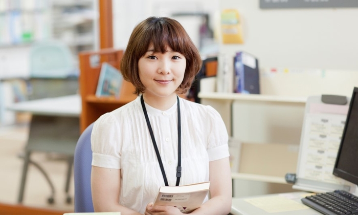 図書館で勤務する司書のイメージ(©︎YUMIK/PIXTA)