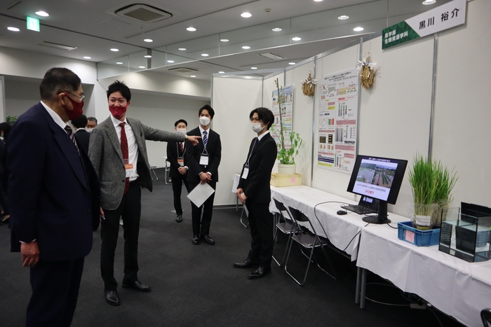 農学部の展示ブースを回る小原学長(左)