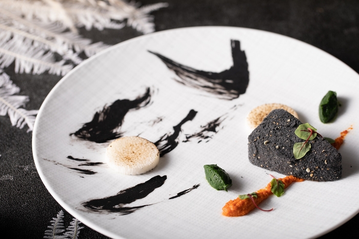 ▲魚料理 思いやり: 寒ブリは別名親ブリとも言われ、越冬と産卵の為、子の為自身を肥えさせる。親が子を持つ思いやりを込めてイカスミソースで皿に模様を描き、ブリが好物のイカを追いかける様を表現しました。