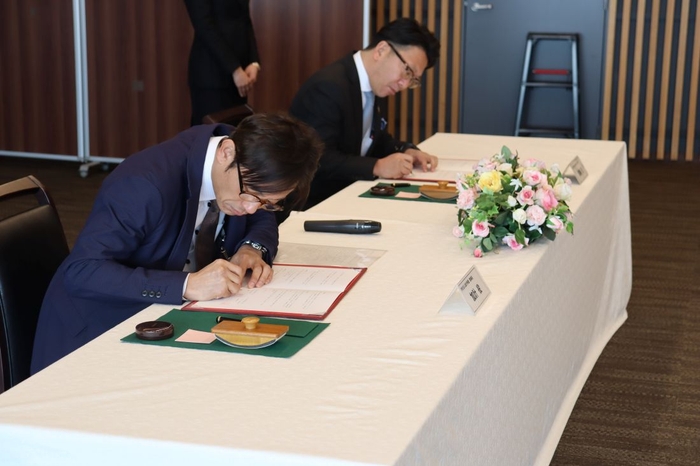 協定書に署名する(左から)加計理事長と尾崎会長