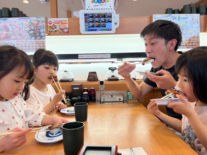 「おかやま理大うなぎ」を美味しそうにほおばる家族連れ(岡山市内のくら寿司で)