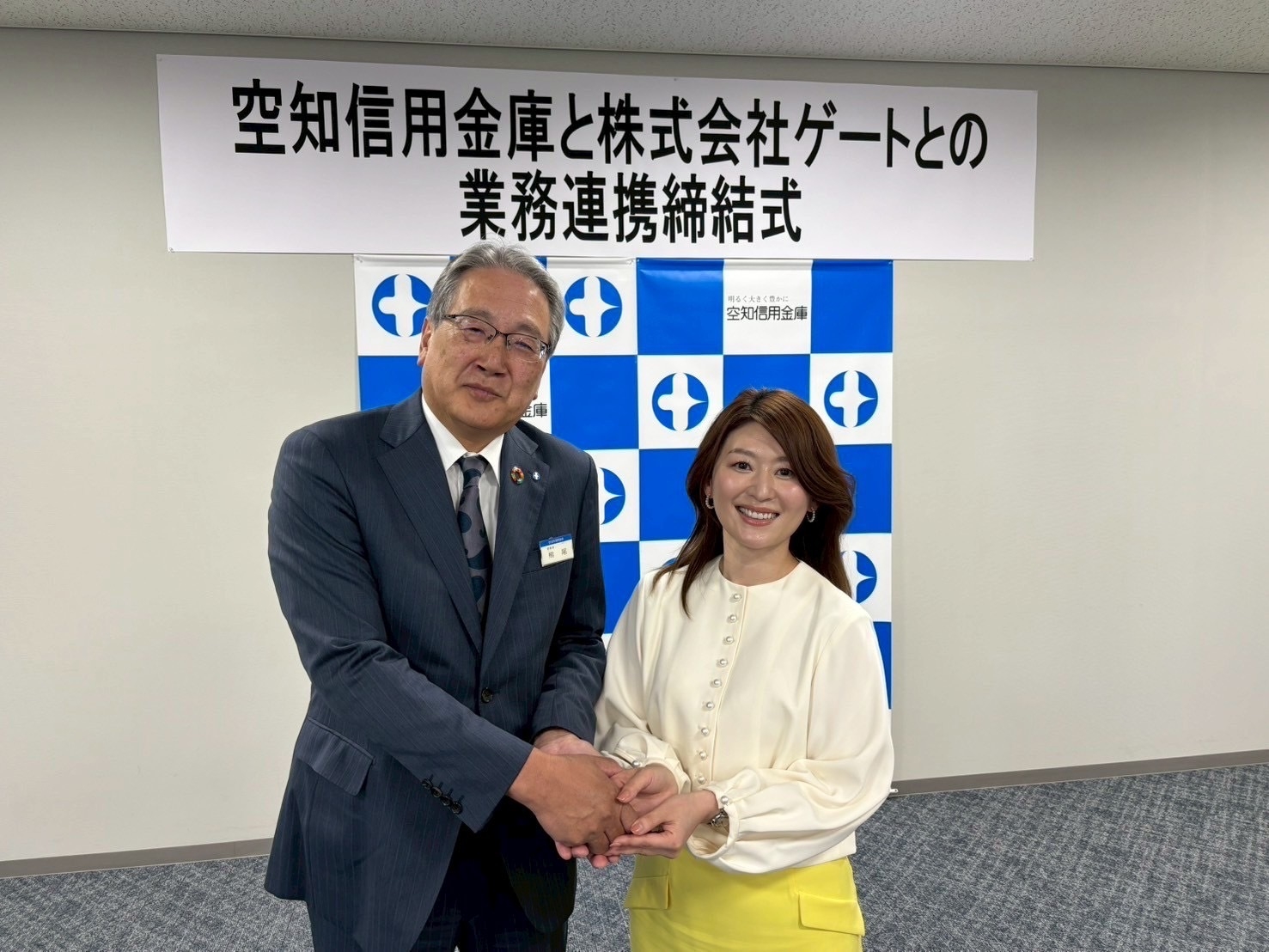 業務提携を締結し笑顔で握手を交わす国井代表取締役(右)と熊尾理事長